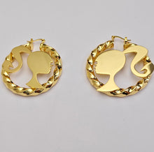 Load image into Gallery viewer, Pair of gold hoop earrings with Barbie Silhouette on a light gray background