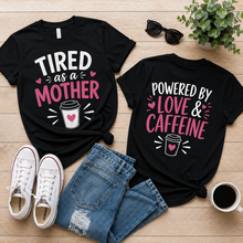 Load image into Gallery viewer, Two black t-shirts with with front and back humorous text designs on a wooden surface with shoes, jeans, and a cup.