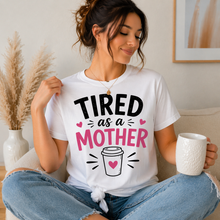 Load image into Gallery viewer, Woman wearing a white t-shirt with 'TIRED as a MOTHER' text and holding a mug.