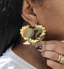 Load image into Gallery viewer, Gold Barbie head heart shaped earring worn by a person with multiple rings on their hand.