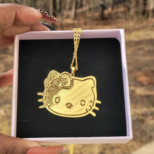 Load image into Gallery viewer, Gold Hello Kitty face-shaped pendant on a chain in a black box held by hands against a blurred background