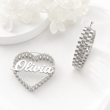 Load image into Gallery viewer, Silver heart-shaped nameplate with 'Olivia' on a white surface with flowers.