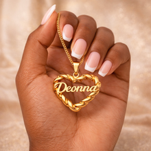 Load image into Gallery viewer, Gold heart-shaped necklace with 'Deonna' engraved, held in a hand against a beige background