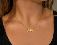 Load image into Gallery viewer, A close-up of a woman's neck and chest wearing a delicate gold chain necklace with a custom script nameplate that reads 'Eagles' in gold lettering.