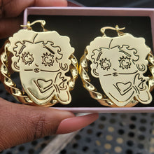 Load image into Gallery viewer, Betty Boop Gold earrings with intricate designs held in a hand in a jewelry box against a black background