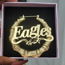 Load image into Gallery viewer, Gold 'Eagles' earrings in a box held by a person