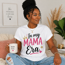 Load image into Gallery viewer, Woman wearing a white t-shirt with 'In my MAMA Era' text, holding a mug, in a cozy indoor setting.