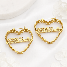 Load image into Gallery viewer, Gold heart-shaped earrings with 'HMU Ladies' text on a white background
