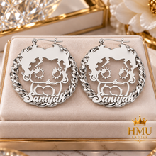 Load image into Gallery viewer, A pair of silver-tone hoop earrings with a custom cutout design featuring a cartoon character and the name 'Saniyah' at the bottom, displayed on a beige jewelry box with a gold HMU Ladies logo in the corner.