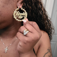 Load image into Gallery viewer, Gold 'Olivia' Hello Kitty earrings held by a person with jewelry on.
