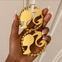 Load image into Gallery viewer, Barbie silhouette twisted style bamboo earrings in a person's hand.