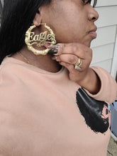 Load image into Gallery viewer, Person wearing 'EAGLES' gold hoop earrings and rings with a blurred background