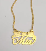 Load image into Gallery viewer, A gold necklace with a pendant featuring the name 'Mia' in a cursive script. The pendant is flanked by two Hello Kitty charms and a heart charm.