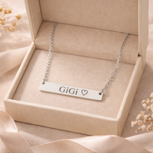 Load image into Gallery viewer, Silver necklace with 'GiGi' engraving in a beige box on a soft fabric background