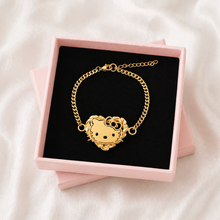 Load image into Gallery viewer, Gold bracelet with a heart-shaped kitty character design in a pink box on a white background
