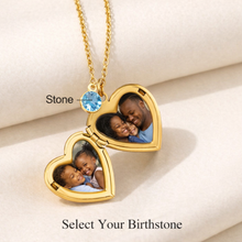 Load image into Gallery viewer, Gold heart-shaped locket with embedded photos and a birthstone on a beige surface.

