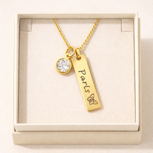 Load image into Gallery viewer, Gold necklace with a pendant and 'Paris' engraved, with a diamond displayed in a box.
