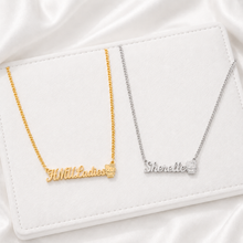 Load image into Gallery viewer, Two nameplate necklaces, one gold and one silver, with kitty at the end of name, on a white surface.
