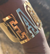 Load image into Gallery viewer, Gold 'EAGLES' cuff bracelet a on a person's wrist with a blurred background 
