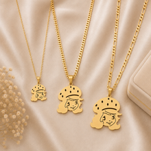 Load image into Gallery viewer, Three gold-tone pendant necklaces with Strawberry Shortcake cartoon character pendants are arranged on a beige satin fabric background, with a small box and dried flowers as styling props.

