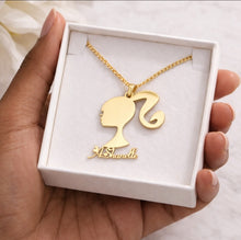 Load image into Gallery viewer, Gold necklace with a Barbie silhouette pendant held in a white box.
