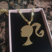 Load image into Gallery viewer, Gold Barbie-shaped pendant with chain on a dark background
