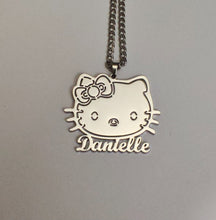 Load image into Gallery viewer, Silver Hello Kitty pendant with 'Dantelle' engraving on a gray background
