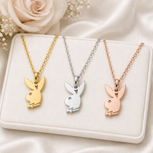 Load image into Gallery viewer, Three Playboy bunny necklaces in gold, silver, and rose gold on a white surface with flowers.
