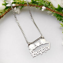 Load image into Gallery viewer, Silver necklace with Kewpie and a heart-shaped pendant and 'Sophia' engraved, against a white background with greenery.
