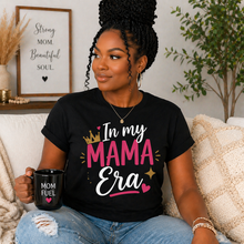 Load image into Gallery viewer, Woman wearing a black t-shirt with 'In my MAMA Era' text, holding a mug, sitting on a couch.
