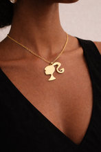 Load image into Gallery viewer, Gold necklace with a pendant featuring a stylized Barbie Silhouette on a person wearing a black top.
