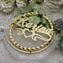 Load image into Gallery viewer, Gold-colored twisted bamboo earrings with a heart bar design, displayed on a glass stand with a floral and lace background.
